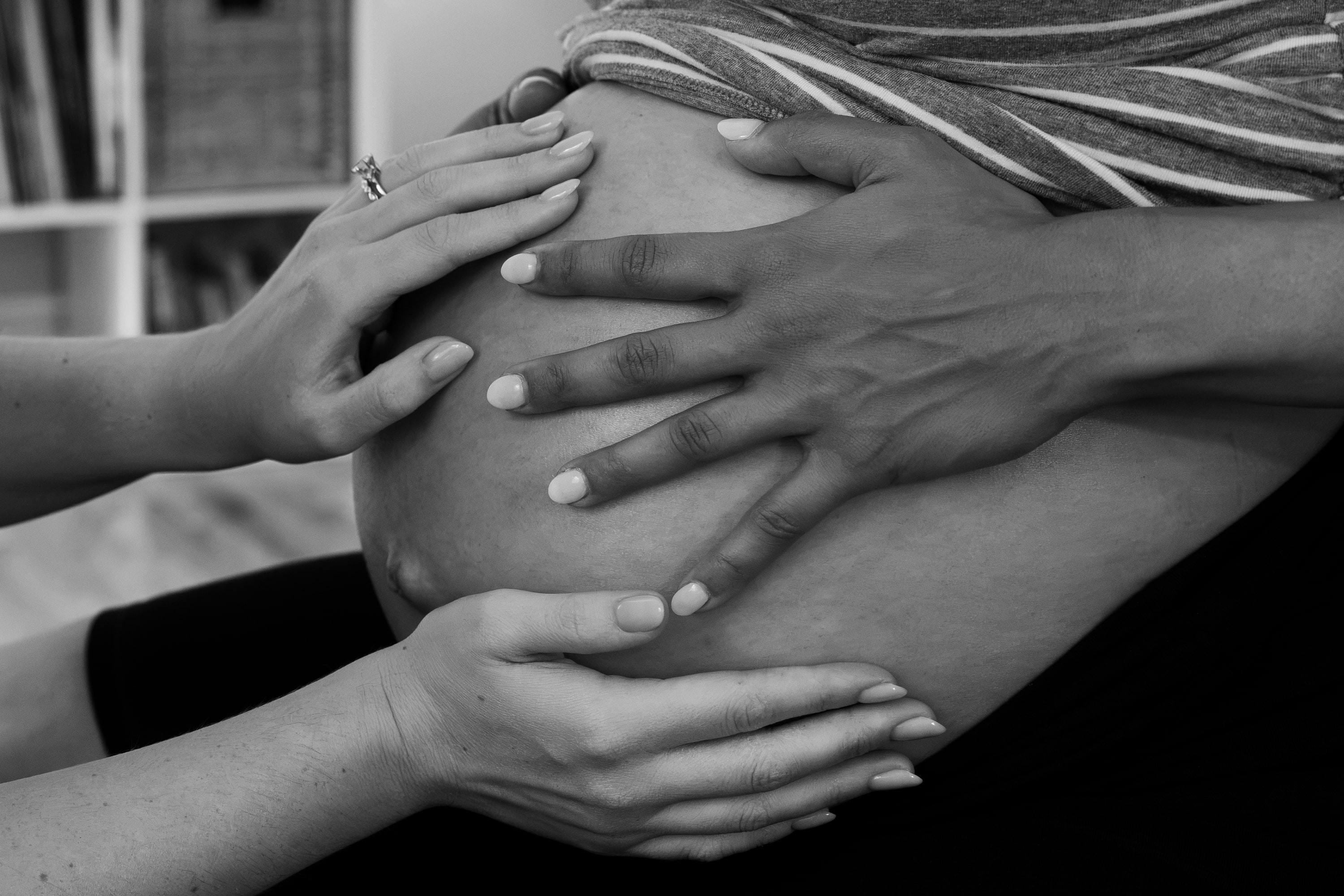 Hands resting together on a client’s pregnant belly